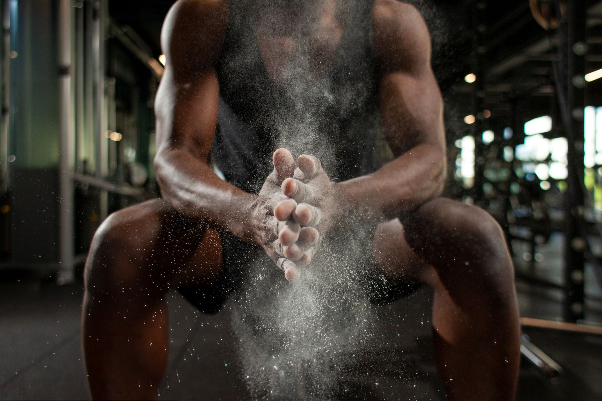 sporty african american man trains in dark gym and rubs his hands with magnesia, young guy makes clap