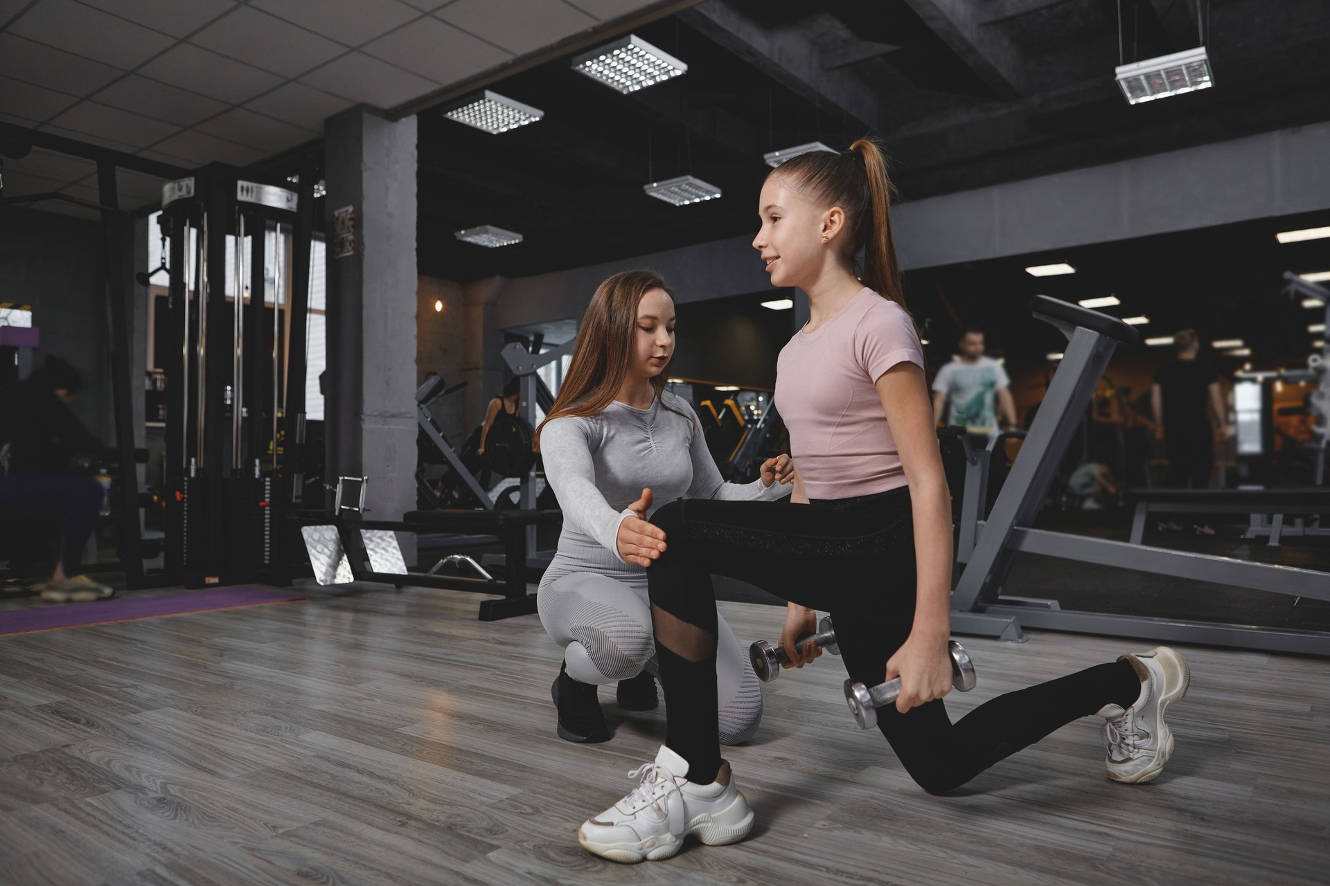 Teenage girl exercising with personal trainer at gym